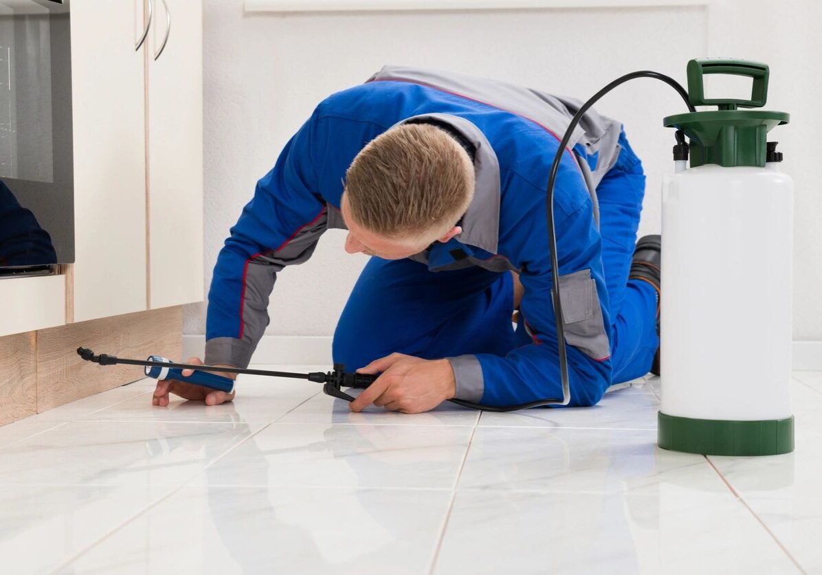 A man in blue work suit working on the floor.